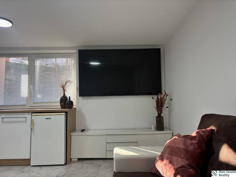 Wohnzimmer in einem Einfamilienhaus mit Fernseher und Sofa, Boden mit Holzdekor.