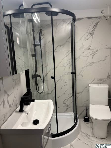 Badezimmer eines Einfamilienhauses mit Marmorverkleidung, Duschkabine und Waschbecken.