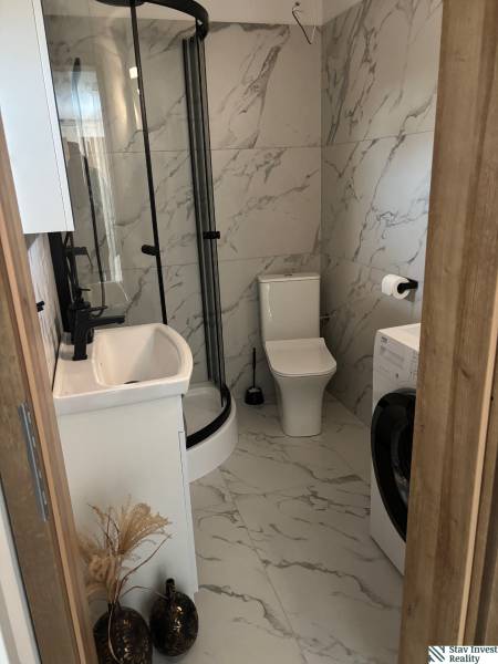 Badezimmer im Einfamilienhaus mit Marmorausstattung, Duschkabine und Waschmaschine.