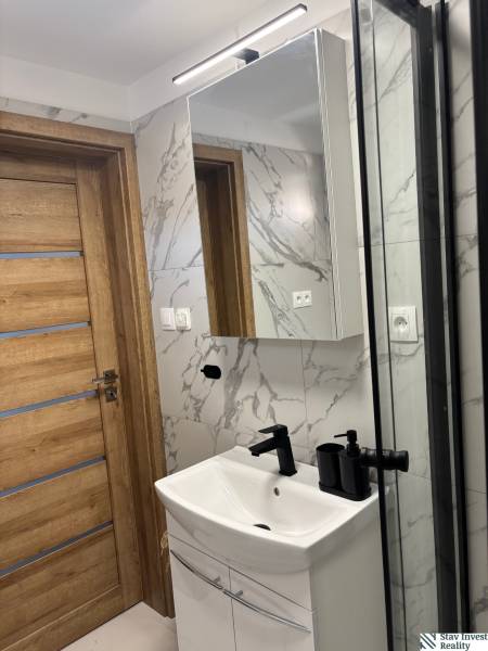 Badezimmer mit Holztüren, Waschbecken und Spiegel in einem Einfamilienhaus.