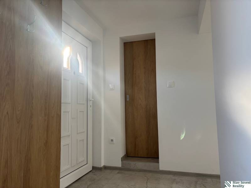 Innenraum eines Einfamilienhauses mit weißen Türen und einem Boden in Holzoptik.