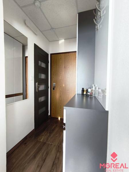 Der Flur mit einem Boden in Holzoptik und weißen Möbeln in einer Einzimmerwohnung.