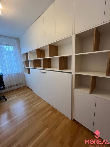 Arbeitszimmer in einer 3-Zimmer-Wohnung mit Regalen und einem Boden in Holzoptik.