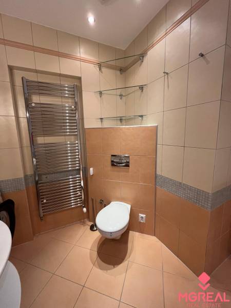 Badezimmer in einer 3-Zimmer-Wohnung mit Fliesen, Toilette, Handtuchheizkörper und Glasregalen.