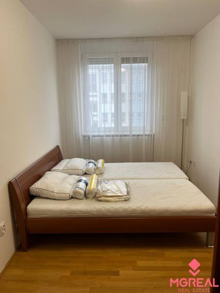 Schlafzimmer in einer 3-Zimmer-Wohnung mit Bett und Fenster, Boden mit Holzdekor.