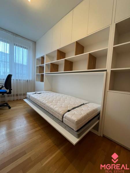 Ein Zimmer in einer 3-Zimmer-Wohnung mit einem Klappbett und einem Boden in Holzoptik.