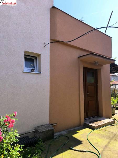 Ein Einfamilienhaus in Partizánske mit farbigem Putz und Garten.