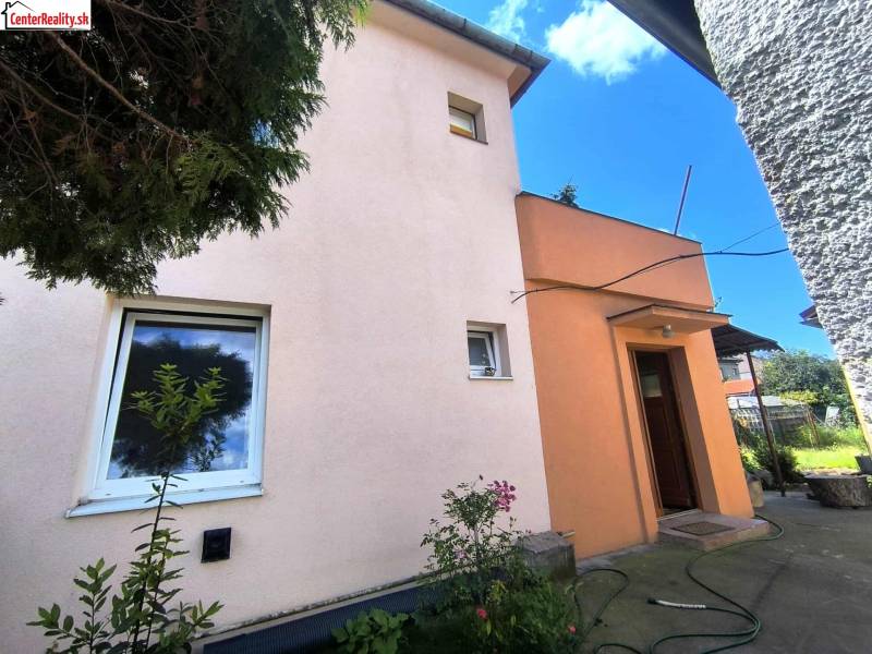 Das Einfamilienhaus in Partizánske hat eine rosa Fassade, kleine Fenster und eine Eingangstür.