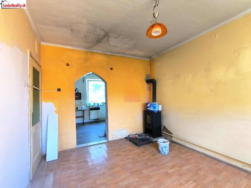 Ein Zimmer im Einfamilienhaus mit Kachelofen und einer Tür zur Küche.