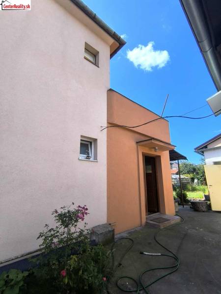 Ein Einfamilienhaus in Partizánske mit einem Hof, Blumen und einem Schlauch auf dem Betonweg.