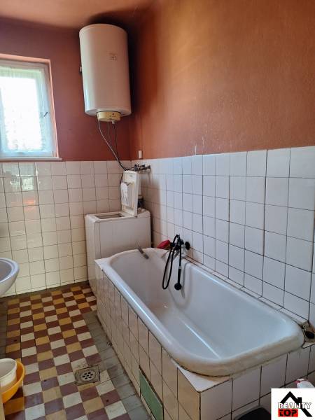 Badezimmer in einem Einfamilienhaus mit Badewanne und Boiler zur Wassererwärmung.