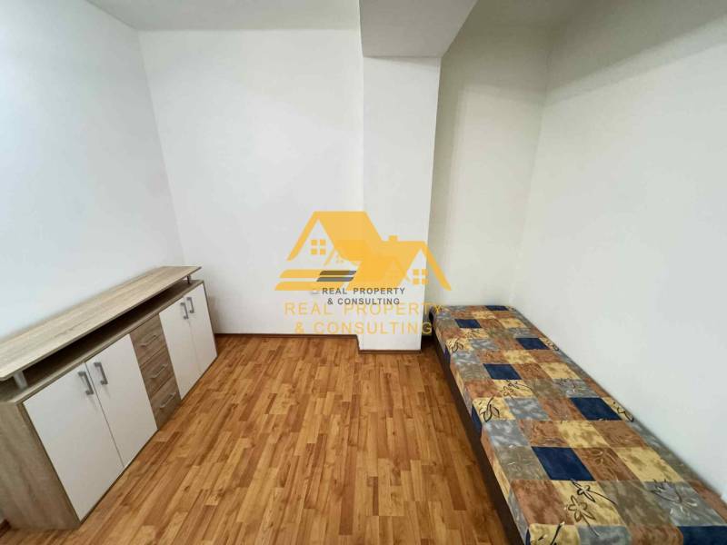 Ein Zimmer in einer 3-Zimmer-Wohnung mit einem Bett, einer Kommode und einem Boden in Holzoptik.