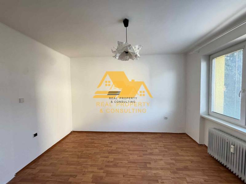 Ein Zimmer in einer 3-Zimmer-Wohnung mit weißen Wänden, einem Boden in Holzoptik und einem Heizkörper.