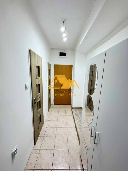 Ein Flur mit weißen Wänden, Fliesenboden und Holztüren in einer 3-Zimmer-Wohnung.