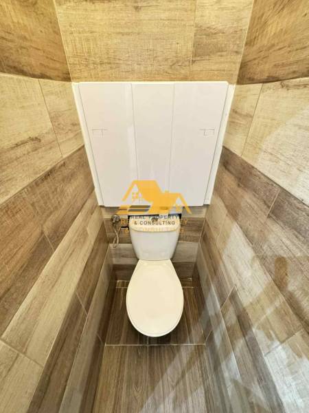 Toilette mit Holzdekorfliesen in einer 3-Zimmer-Wohnung.