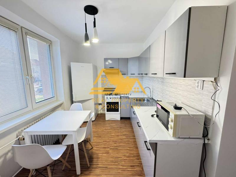 Küche in einer 3-Zimmer-Wohnung mit weißen Schränken und einem Boden in Holzoptik.