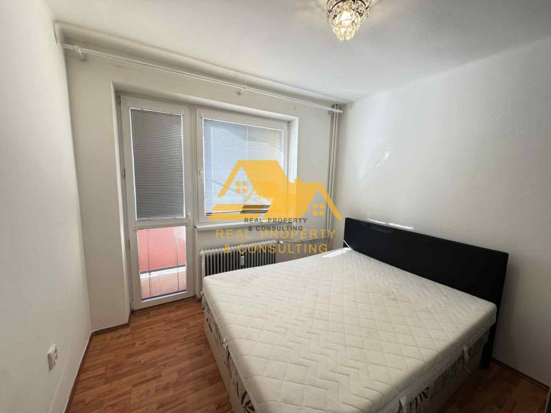 Schlafzimmer in einer 3-Zimmer-Wohnung mit Bett, Fenster und Boden in Holzoptik.