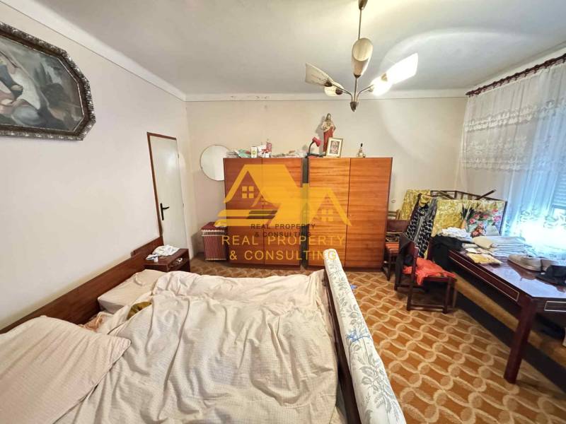 Schlafzimmer in einem Einfamilienhaus mit Bett, Schrank und Teppich mit geometrischem Muster.