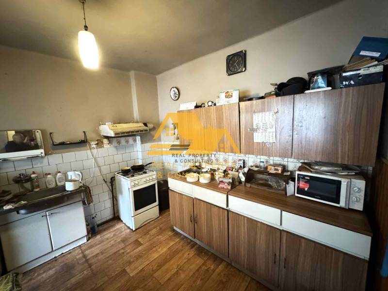 Küche in einem Einfamilienhaus mit Holzdekorboden, Küchenzeile, Geräten, Aufbewahrungsschränken.