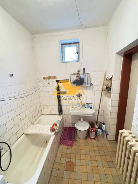 Badezimmer in einem Einfamilienhaus mit Badewanne, Waschbecken, Heizkörper und Fliesenboden.