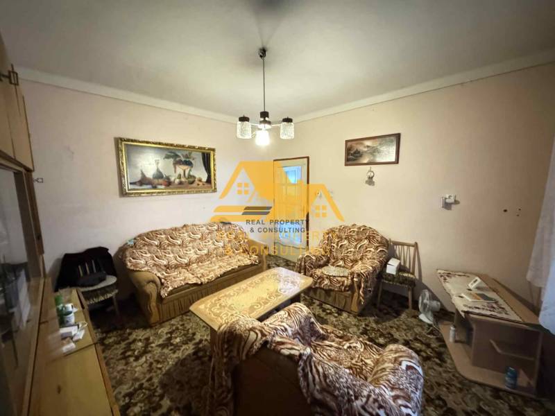 Wohnzimmer in einem Einfamilienhaus mit Sofa und Sesseln, dekoriert mit Bildern.