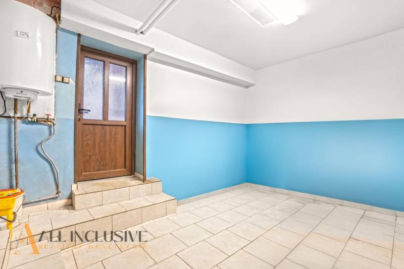 Das Innere eines Einfamilienhauses mit blauen Wänden und hellem Boden neben einer Holztür.