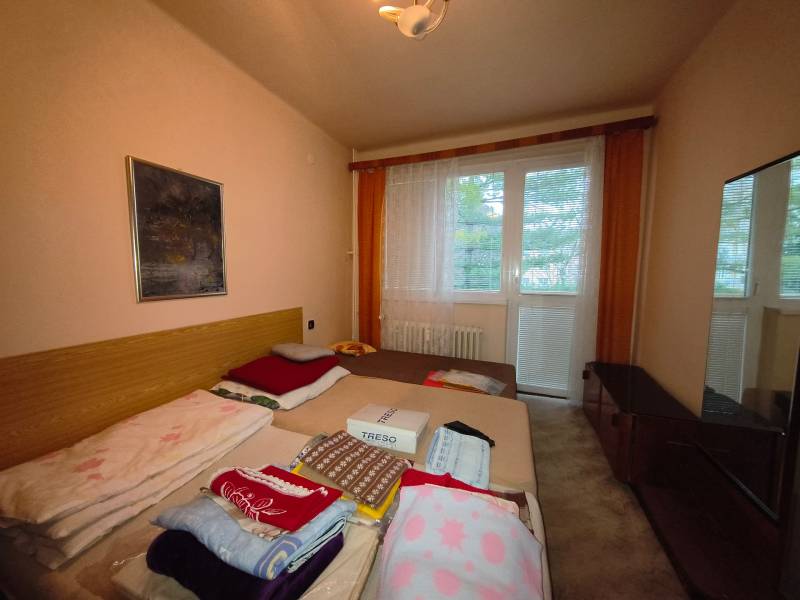 Schlafzimmer in einer 3-Zimmer-Wohnung mit Bett, Bild und großem Fenster mit Aussicht.