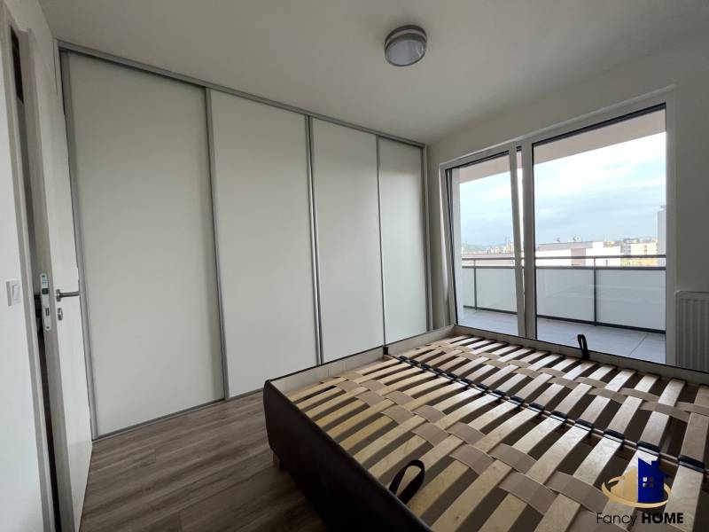 Schlafzimmer in einer 2-Zimmer-Wohnung mit großem Einbauschrank und Balkon, Boden mit Holzdekor.
