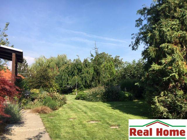 Ein Garten bei einem Einfamilienhaus in Čierna Voda mit reicher Bepflanzung und gepflegtem Rasen.