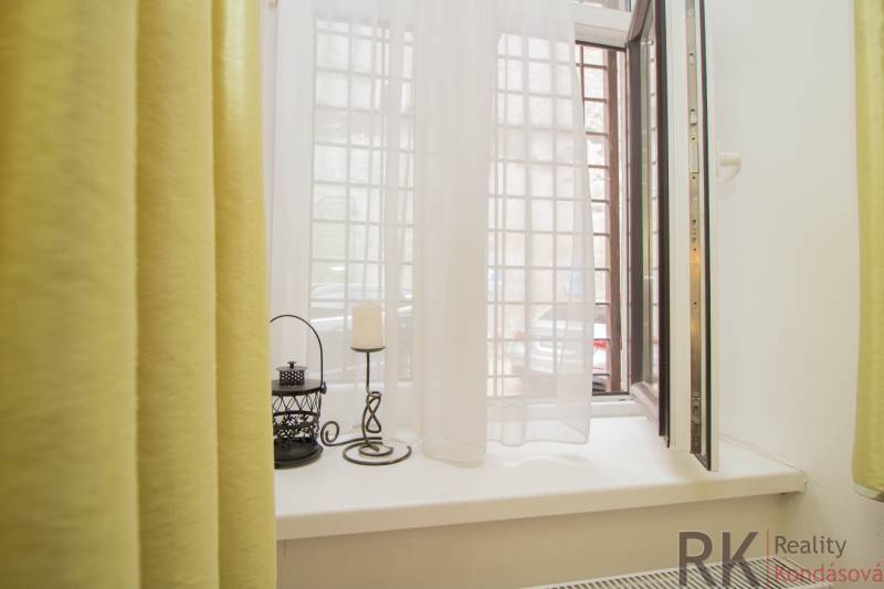 Ein offenes Fenster in einer Zweizimmerwohnung mit Vorhängen und Dekorationen auf der Fensterbank.