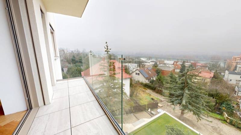 Balkon mit verglastem Geländer in einem Einfamilienhaus mit Blick auf die Umgebung.
