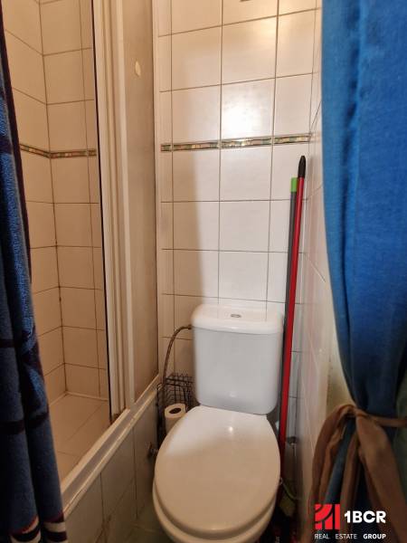 Badezimmer in einem Studio-Apartment mit Toilette und Duschkabine, Fliesen mit dekorativem Element.
