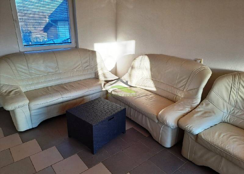 Beiges Sofa in der Hütte mit einem Rattantisch, Sonnenlicht durch das Fenster.