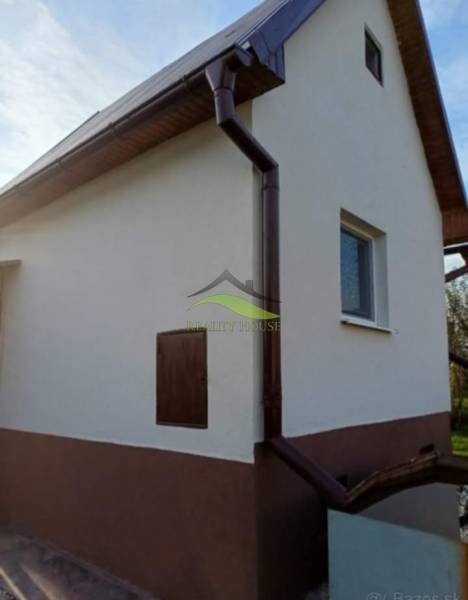 Ein Ferienhaus in Pozdišovce mit weißer Fassade und dunklem Dachrinnensystem.