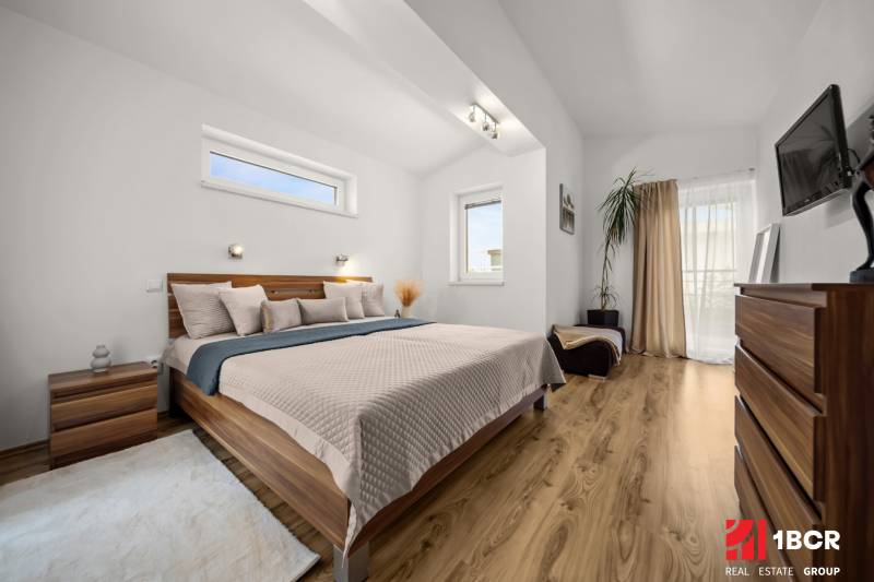 Schlafzimmer in einem Einfamilienhaus mit Bett, dekorativen Elementen und Boden mit Holzdekor.