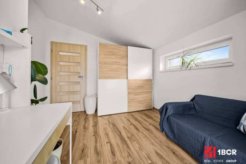 Ein Zimmer in einem Einfamilienhaus mit einem Boden in Holzoptik, einem Schrank und einem Sofa.