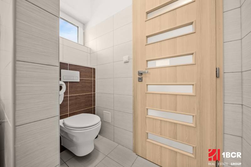 Toilette in einem Einfamilienhaus mit hellen Fliesen und Türen mit vertikalen Streifen.