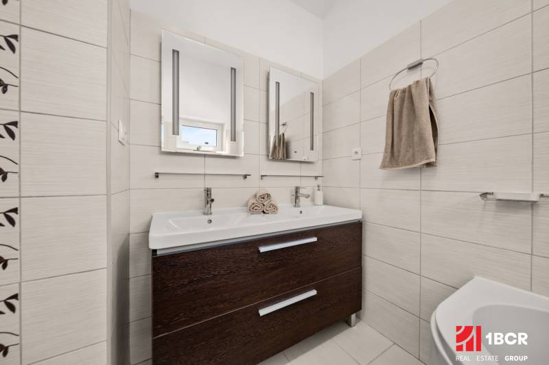 Badezimmer in einem Einfamilienhaus mit Doppelwaschbecken und dunklem Schrank.