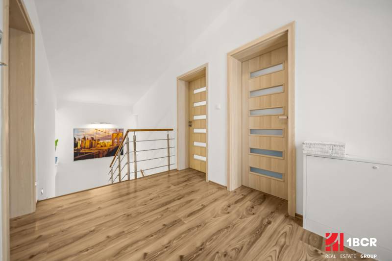 Flur in einem Einfamilienhaus mit Holzboden, minimalistischem Geländer und einem Kunstfoto.