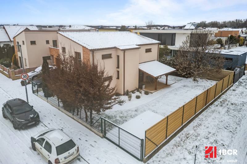 Einfamilienhaus in Bratislava - Čunovo in der Straße Konopiská, verschneite Straße, geparkte Autos.