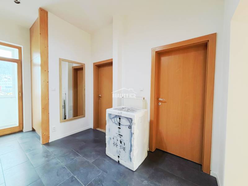 Der Flur in einer 2-Zimmer-Wohnung mit dunklem Boden und Holztüren.