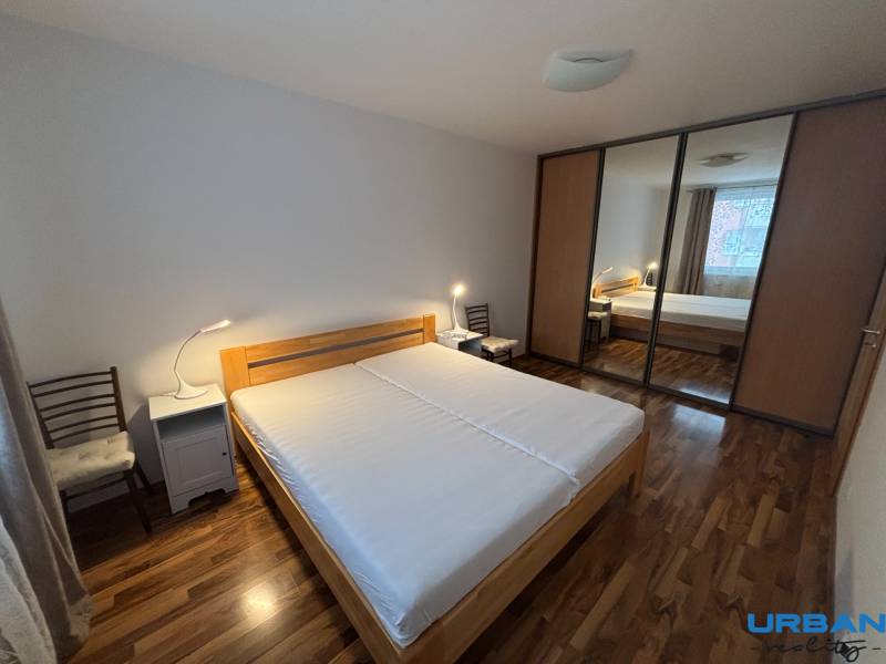 Schlafzimmer mit Bett, Schrank mit Schiebetüren und Boden mit Holzdekor.