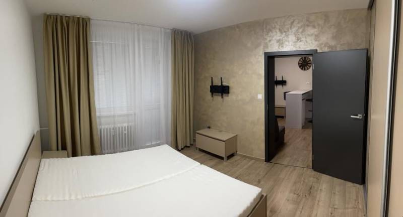 Schlafzimmerbereich mit Bett, Vorhängen und Holzboden in einer Einzimmerwohnung.