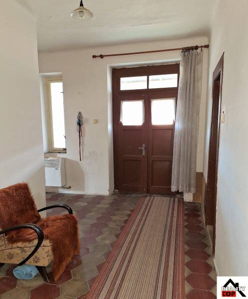 Der Flur eines Einfamilienhauses mit Fliesenboden, einem Sessel und einem Vorhang.