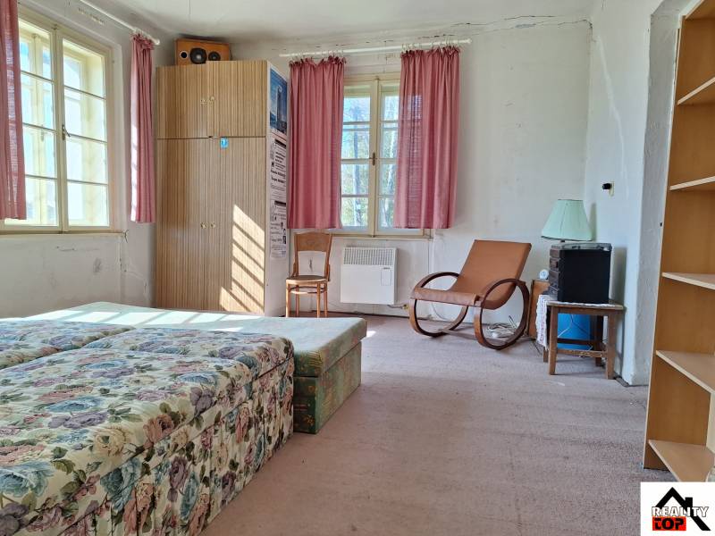 Ein Zimmer mit einem Blumensofa, einem Sessel, einem Schrank und rosa Vorhängen in einem Einfamilienhaus.