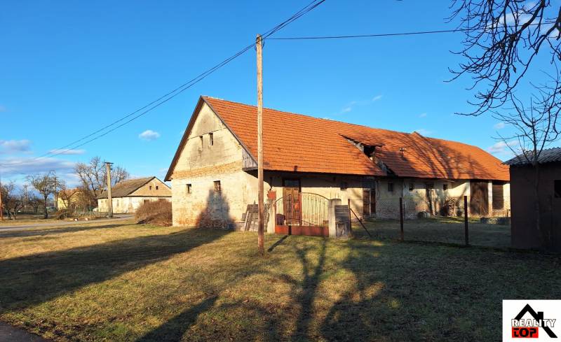 Ein Steinhaus für die Familie in Orávka mit einem roten Dach, umgeben von einem grasbewachsenen Grundstück.
