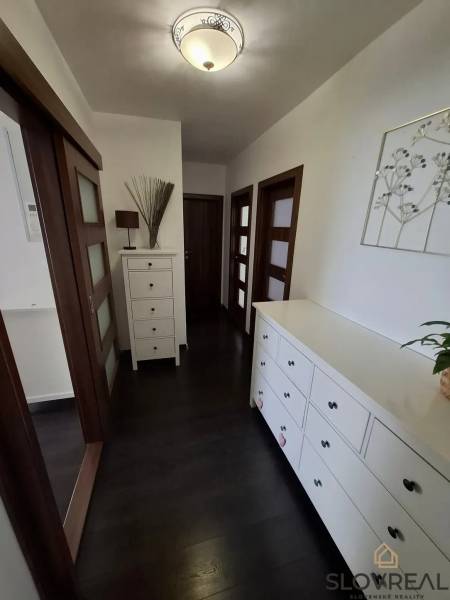 Flur in einer 3-Zimmer-Wohnung mit dunklem Boden und weißen Möbeln.