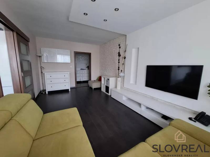 Wohnzimmer in einer 3-Zimmer-Wohnung mit Holzboden, Fernseher und Sitzgarnitur.