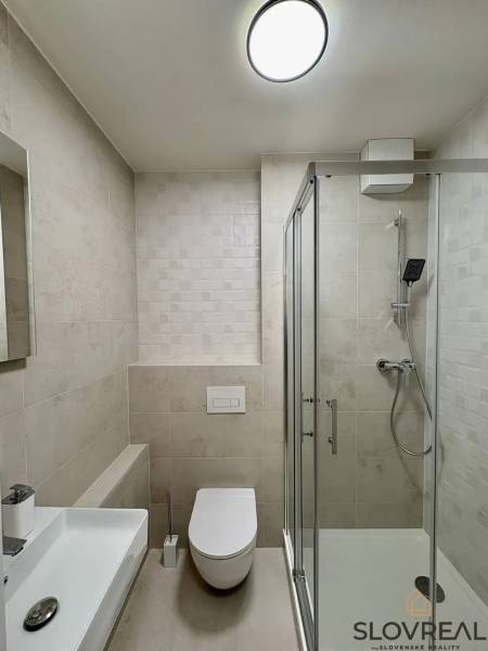 Badezimmer mit Toilette und modernem Duschkabine in einer 3-Zimmer-Wohnung.