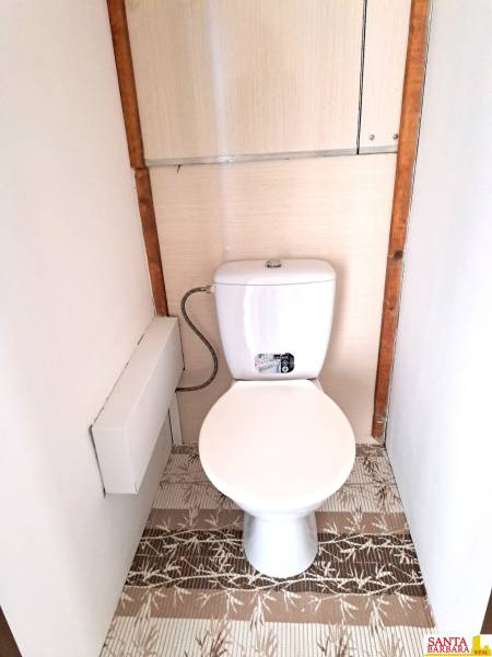 Toilette mit weißem Spülkasten und Boden in Holzoptik in einer 4-Zimmer-Wohnung.